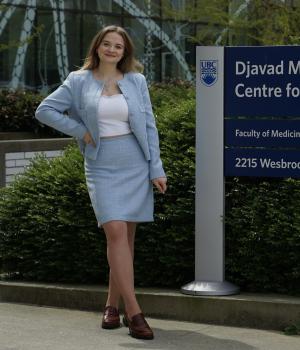 Woman wearing blue blazer and dress standing next to the sign of the Djavad Mowafaghian Centre for Brain Health
