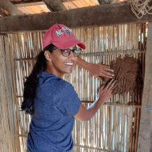 girl with her hands on a wall inside a hut